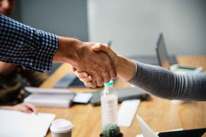 two person doing handshake beside table inside room